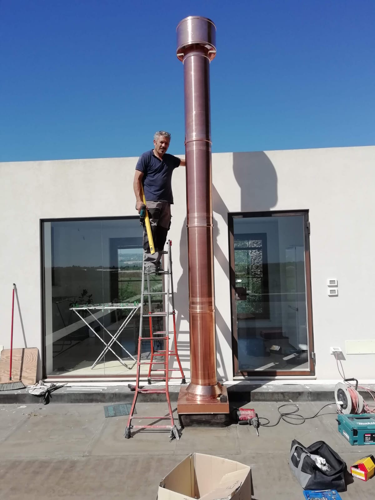 Tecnico di Punto Fuoco al lavoro sull'installazione di una canna fumaria in rame all'esterno di un'abitazione