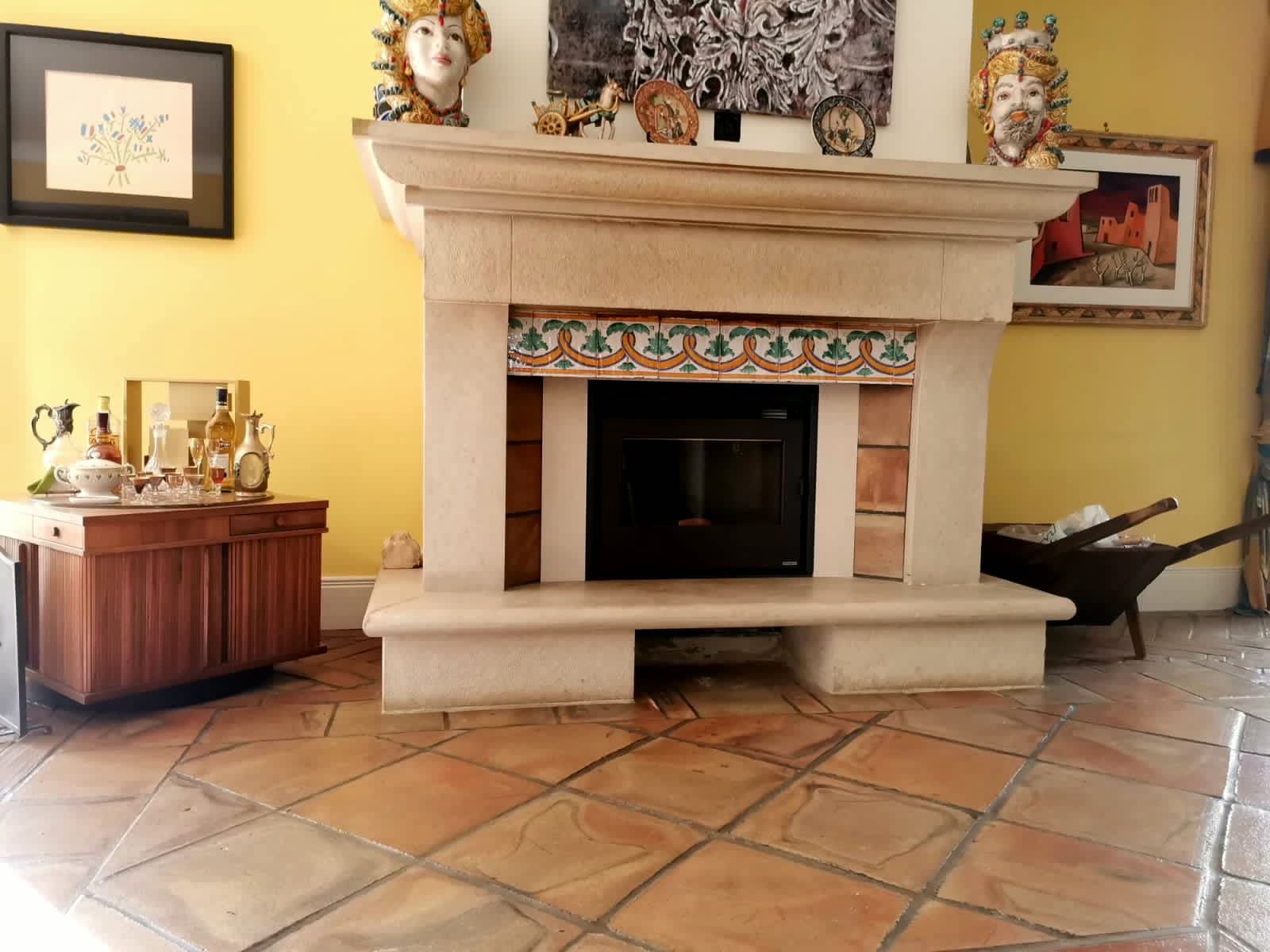 Caminetto con cornice classica in pietra e fascia di ceramiche decorate in un salone siciliano